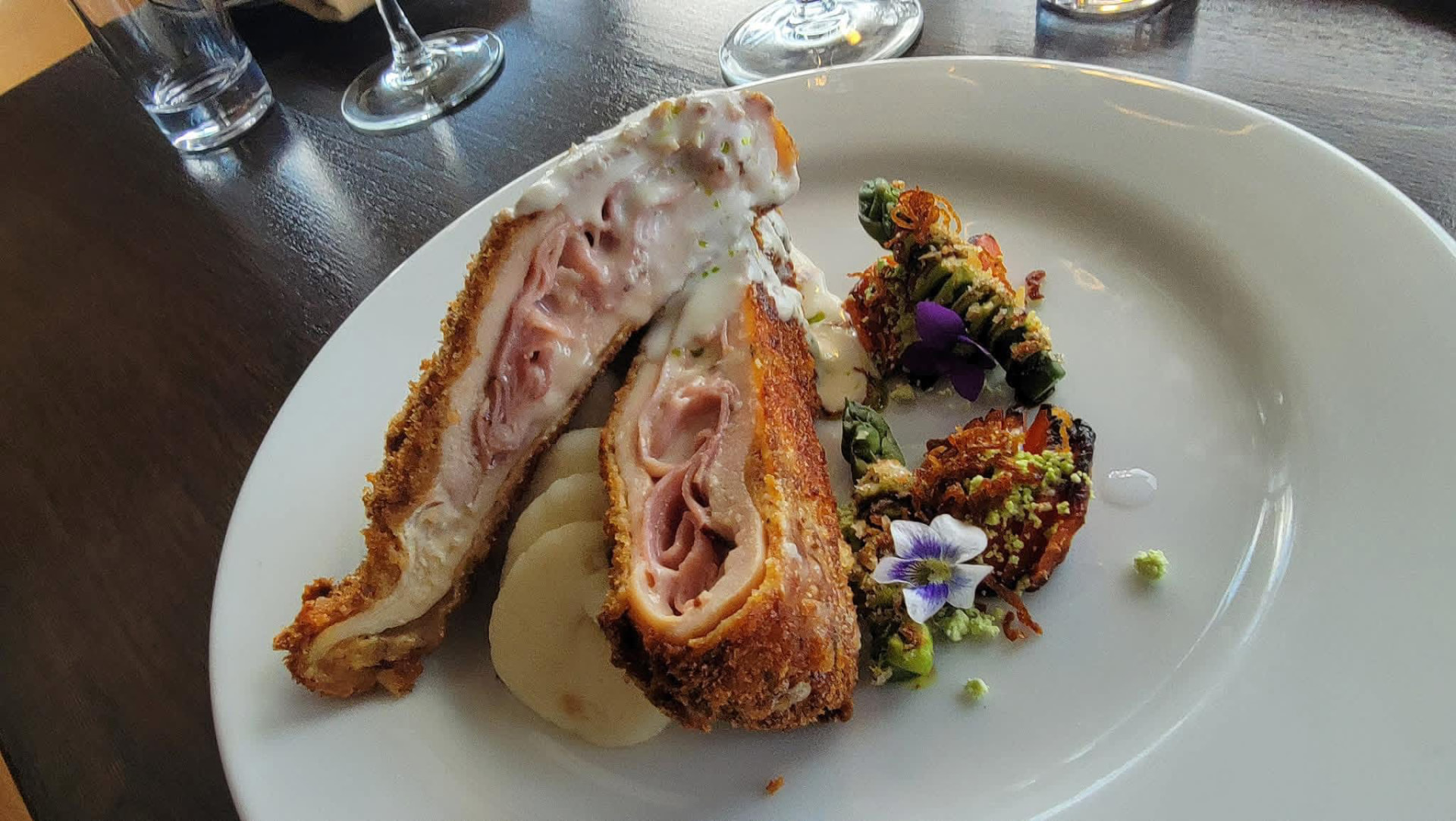 A stuffed chicken course plated with mustard cream and glazed vegetables